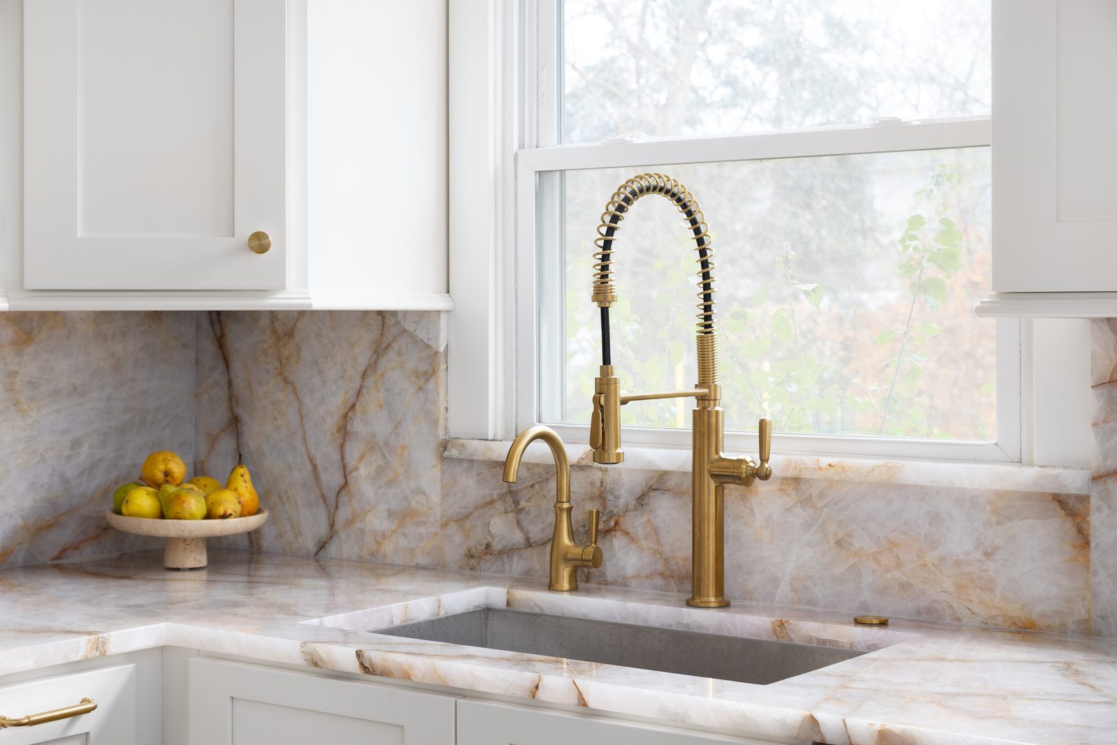 Gold-veined quartzite backsplash and waterfall counter with brass fixtures